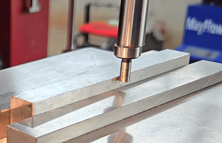 Edge finder tip spinning and approaching the edge of a metal workpiece during setup.